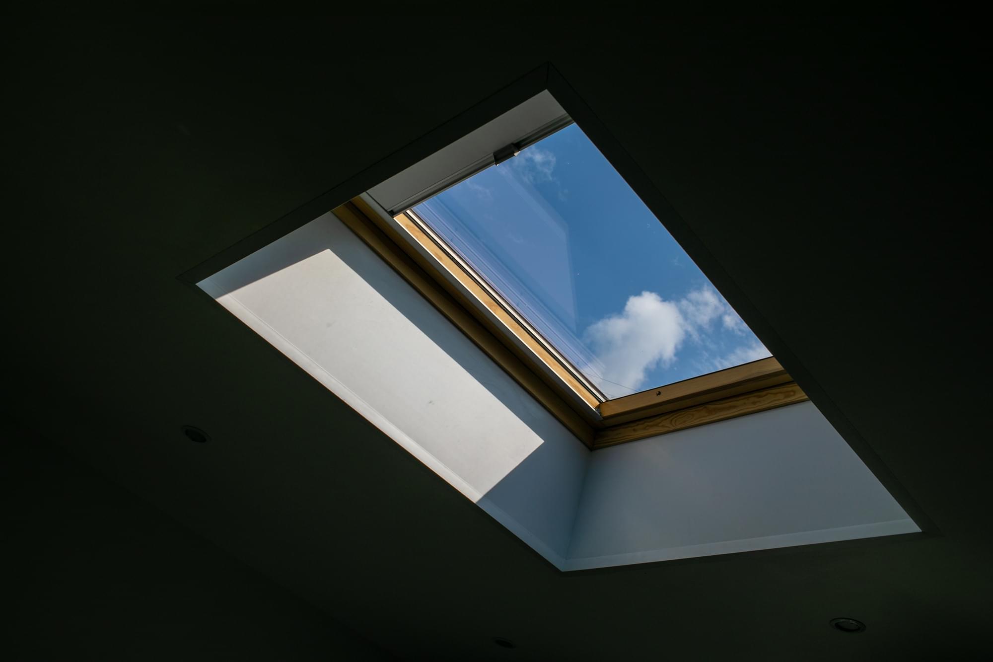 looking up blue cloudy sky through modern square ceiling window web